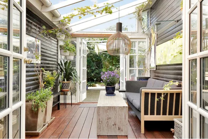 Plant filled Scandinavian sunroom with wooden elements